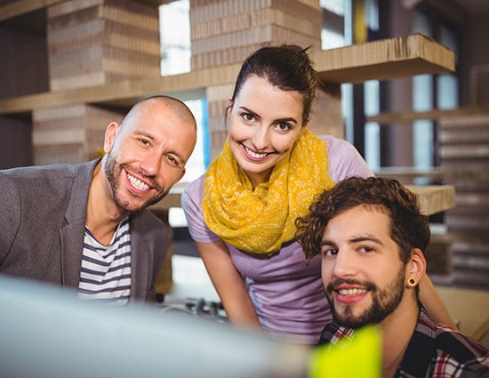 Three smiling colleagues looking at a screen together in a studio